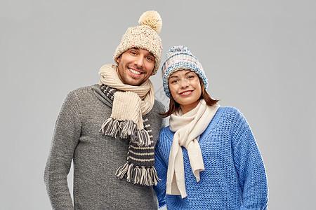 幸福的夫妇针帽围巾灰色背景穿着冬天衣服的快乐夫妇服装高清图片素材